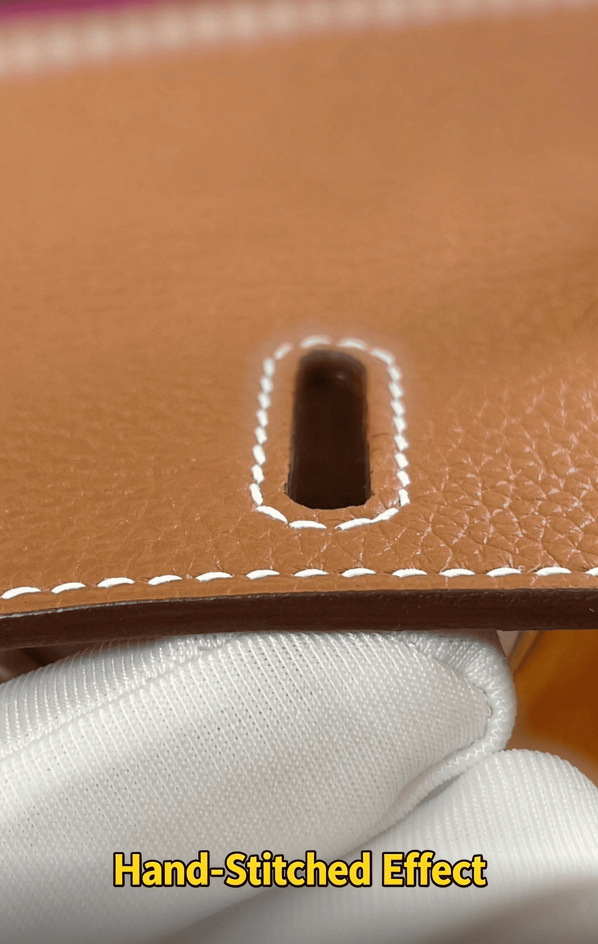 Hand-stitched leather effect, precise white stitching around leather hole, tan calfskin texture, luxury bag craftsmanship detail, hand sewing technique for high-end accessories