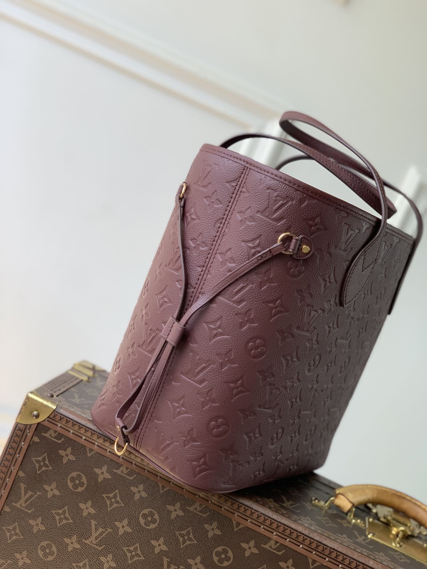 LV Neverfull Empreinte burgundy designer tote bag side view, adjustable leather drawstring and gold hardware