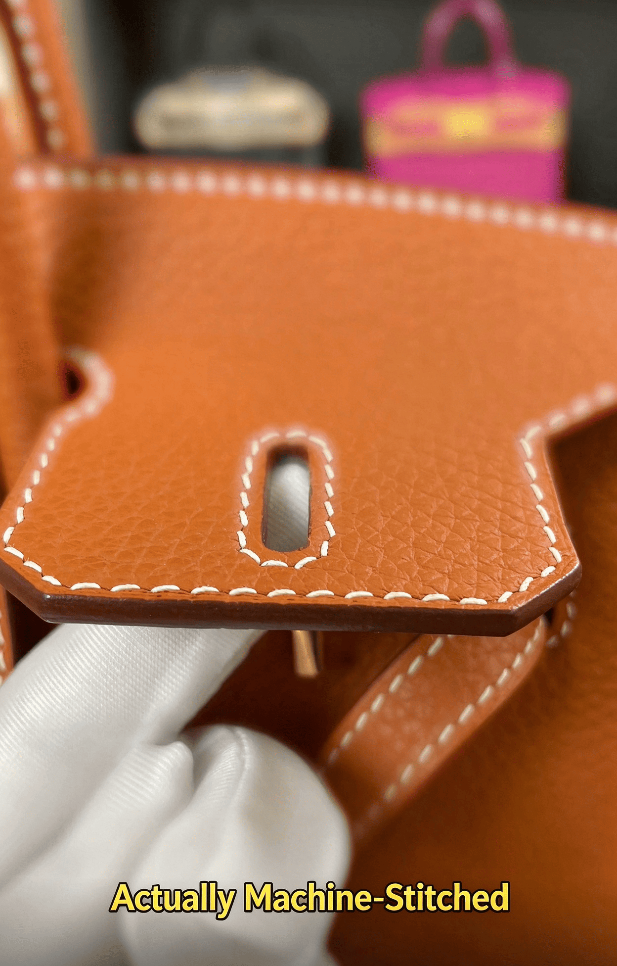 Actually machine-stitched leather detail, orange calfskin, precise white stitching around hardware hole, luxury bag construction, industrial stitching technique, craftsmanship comparison